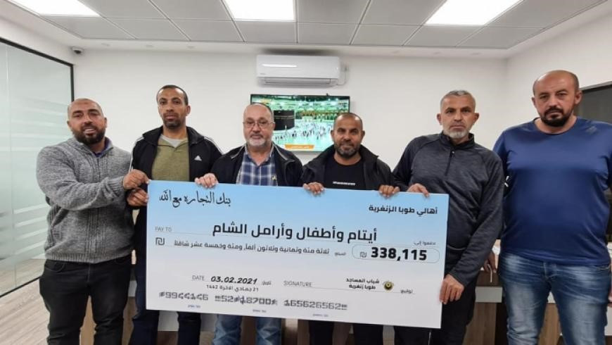 أهالي من قرية طوبا الفلسطينية يحملون بوستر عليه المبلغ الذي تم جمعه لصالح اللاجئين السوريين